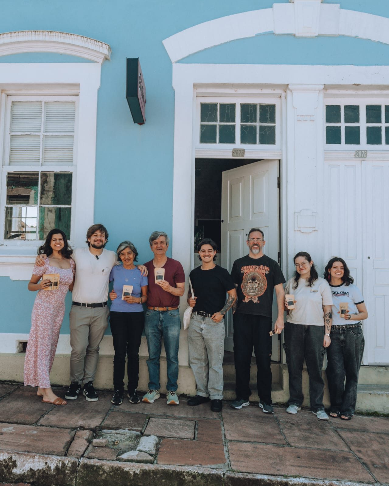 Turma reunida na frente de um casarão azul